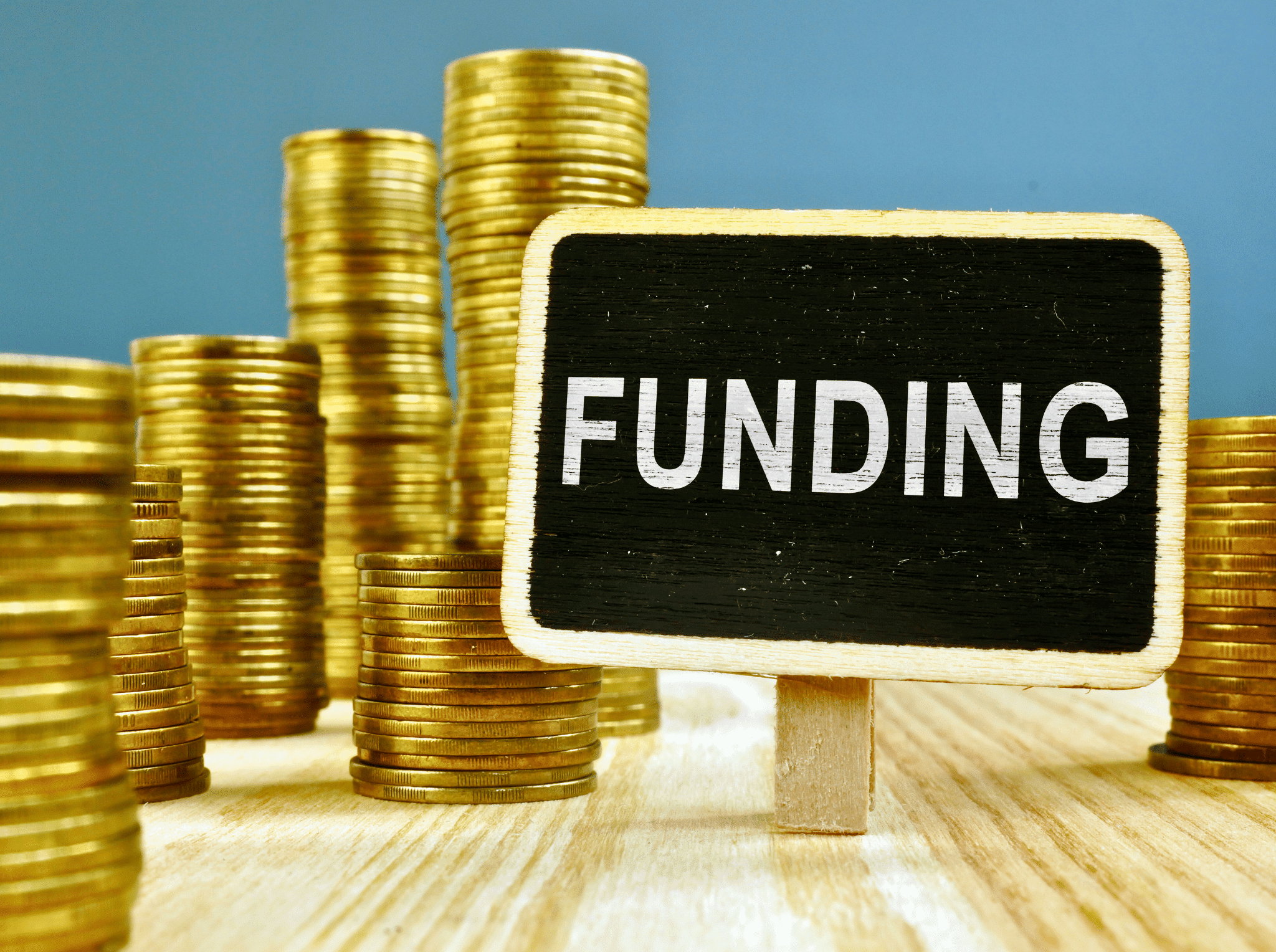 A funding sign placed in front of coins stacked into towers.